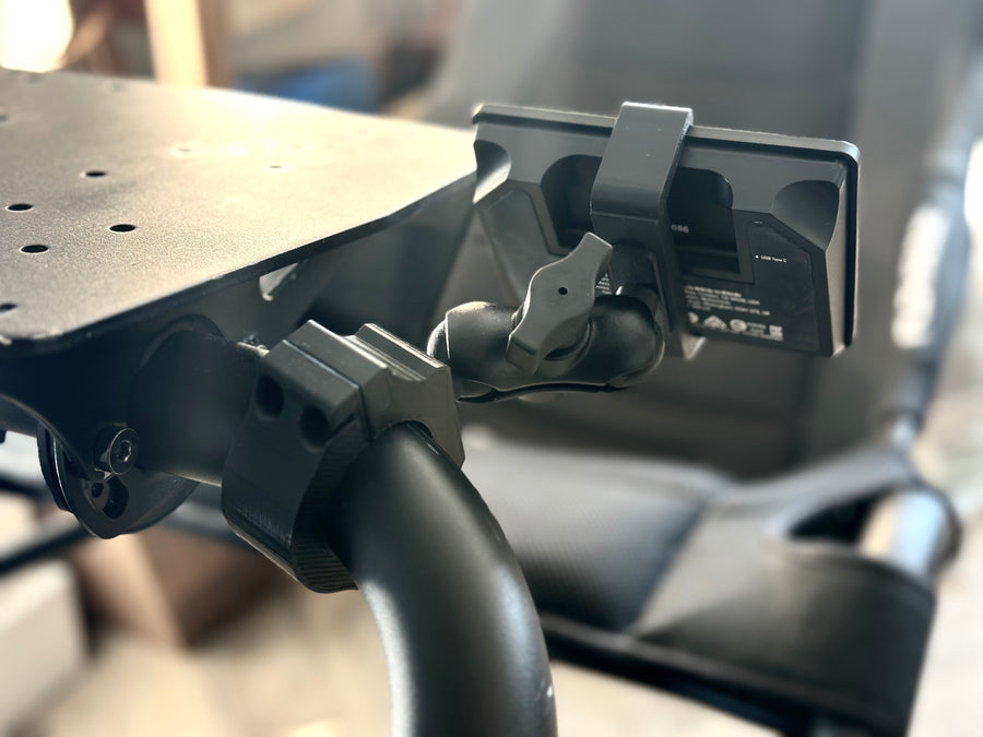 Playseat Trophy Stream Deck Mount installed on the tubular cockpit frame with a 15-key Stream Deck or Stream Deck Plus positioned beside the driving seat. The clamp attaches directly to the Playseat Trophy tube, while the RAM arm brings race controls into reach. This adjustable sim racing mount is available with a compact 5.5 cm arm or a longer 9.5 cm RAM arm for additional reach.