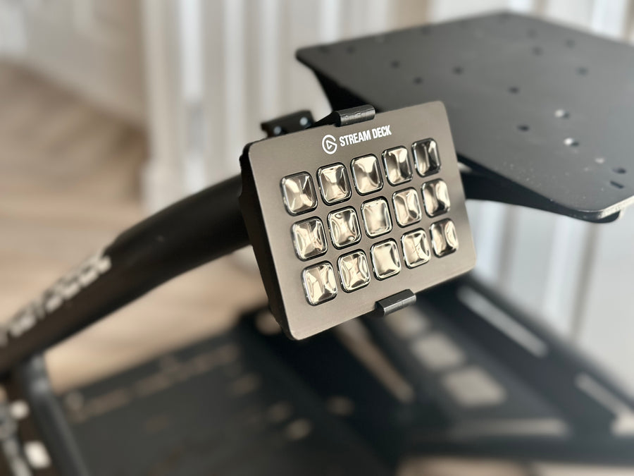 Playseat Trophy Stream Deck Mount installed on the tubular cockpit frame with a 15-key Stream Deck or Stream Deck Plus positioned beside the driving seat. The clamp attaches directly to the Playseat Trophy tube, while the RAM arm brings race controls into reach. This adjustable sim racing mount is available with a compact 5.5 cm arm or a longer 9.5 cm RAM arm for additional reach.