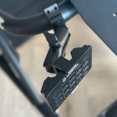 Playseat Trophy Stream Deck Mount close-up showing the tube clamp secured around the tubular cockpit frame. The purpose-built clamp creates a stable mounting point for the adjustable RAM arm without drilling into the Playseat Trophy. All required mounting hardware is included, allowing a 15-key Stream Deck or Stream Deck Plus to be positioned beside the driver for sim racing controls.